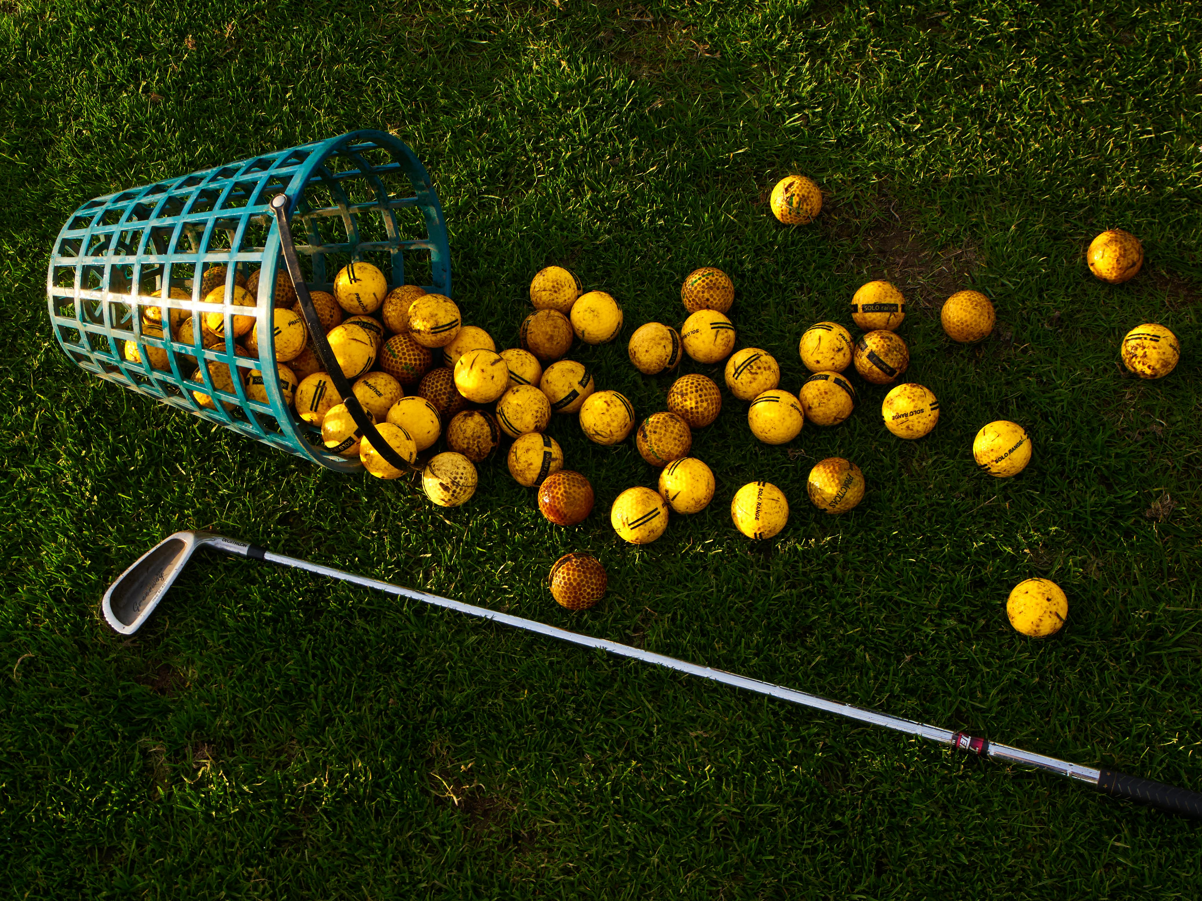 Premium golf balls and club on fairway-style grass, showcasing professional golf equipment.